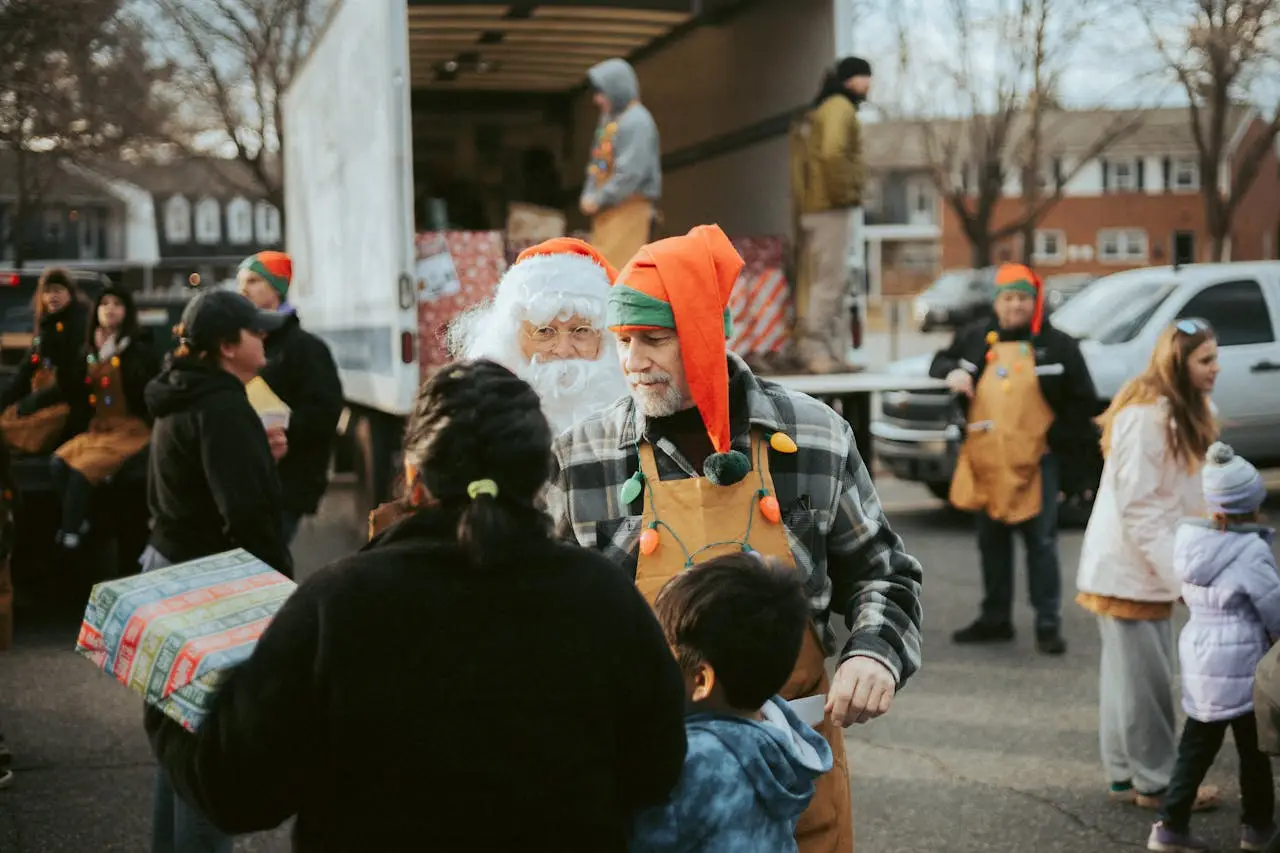 Santa and volunteers distribute gifts from a truck in a community Christmas event.