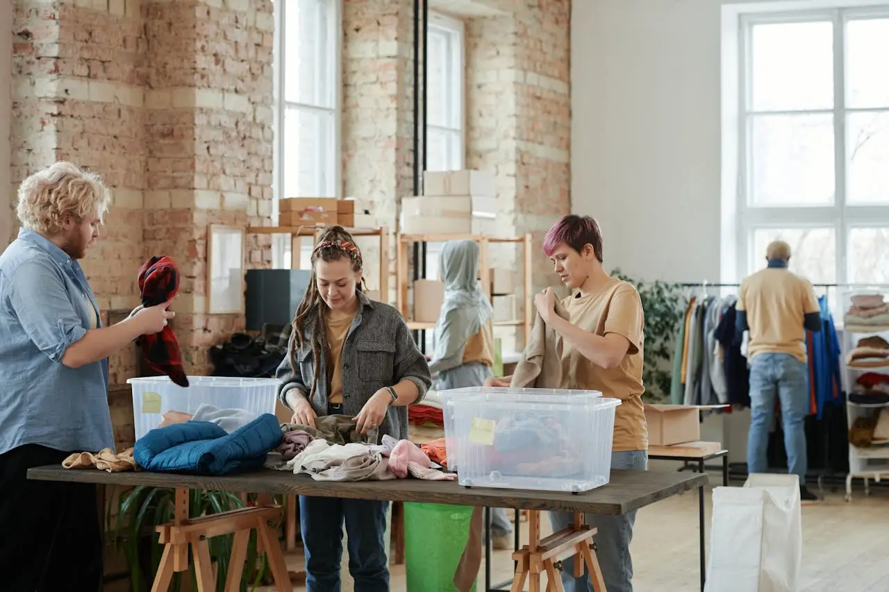 Volunteers organizing clothes in a bright, rustic donation center indoors.