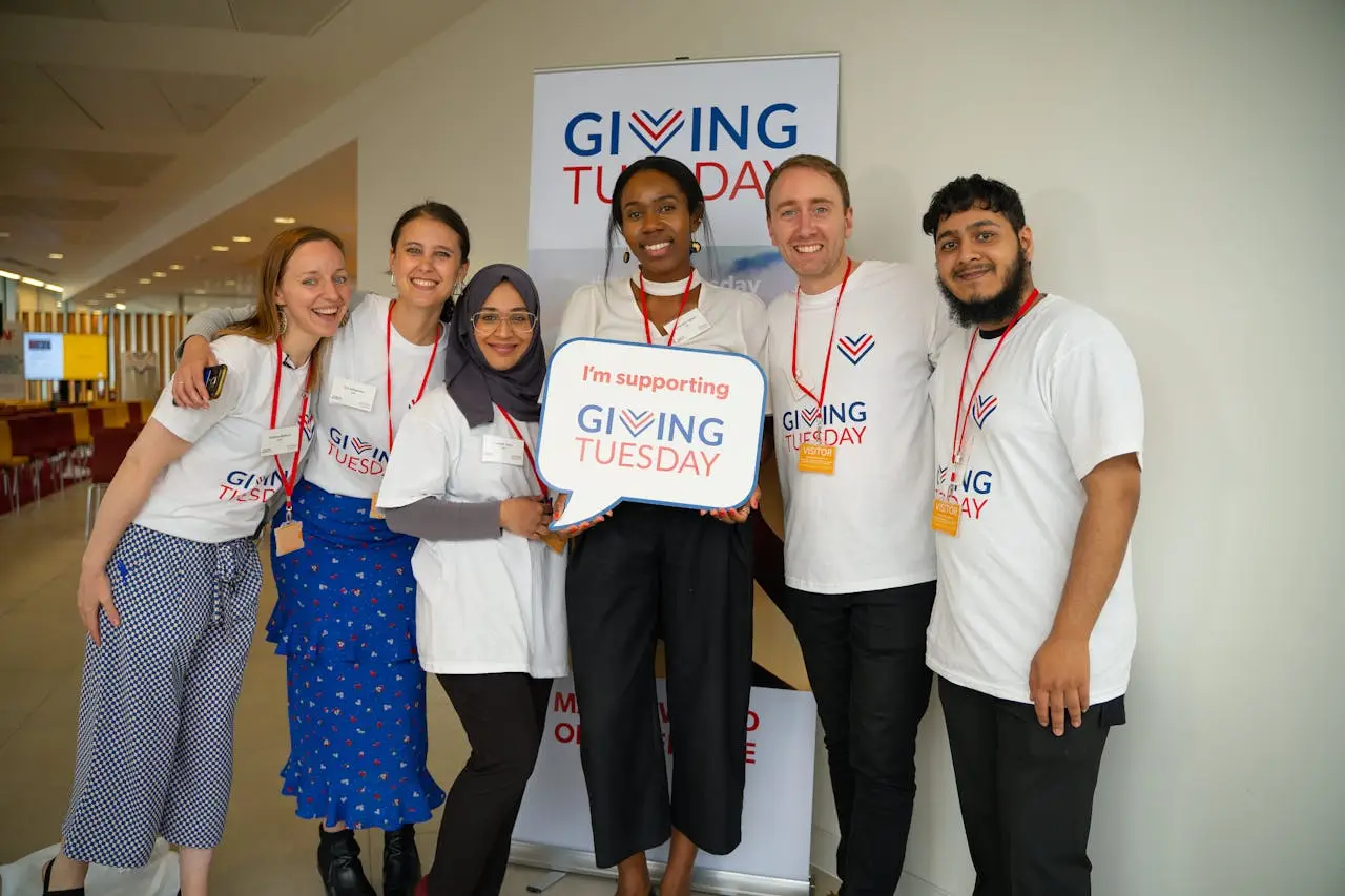 Diverse group of adults supporting Giving Tuesday with enthusiasm indoors.